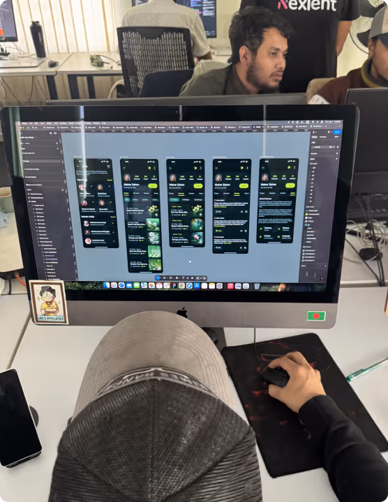 Someone in a cap working on a mobile app design while others work behind.