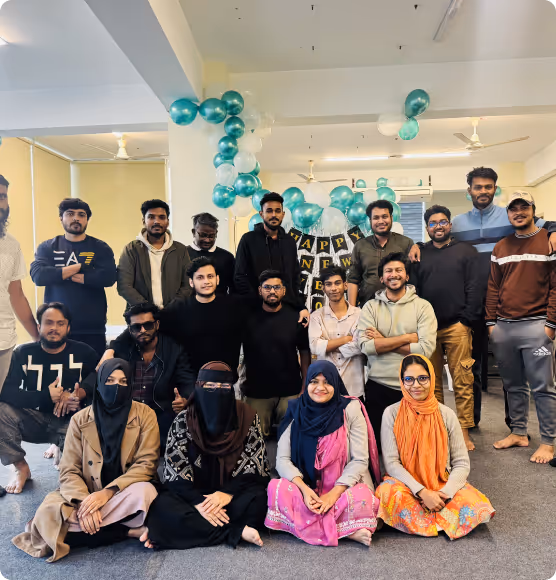 The team gathered indoors with balloons and a New Year sign behind them.