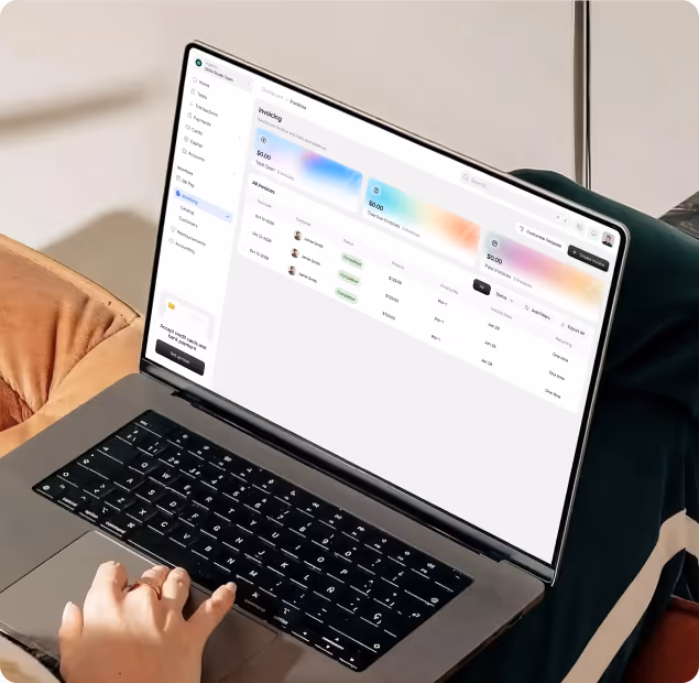 Person using a laptop showing an invoice management dashboard with a list of invoices and summary metrics.